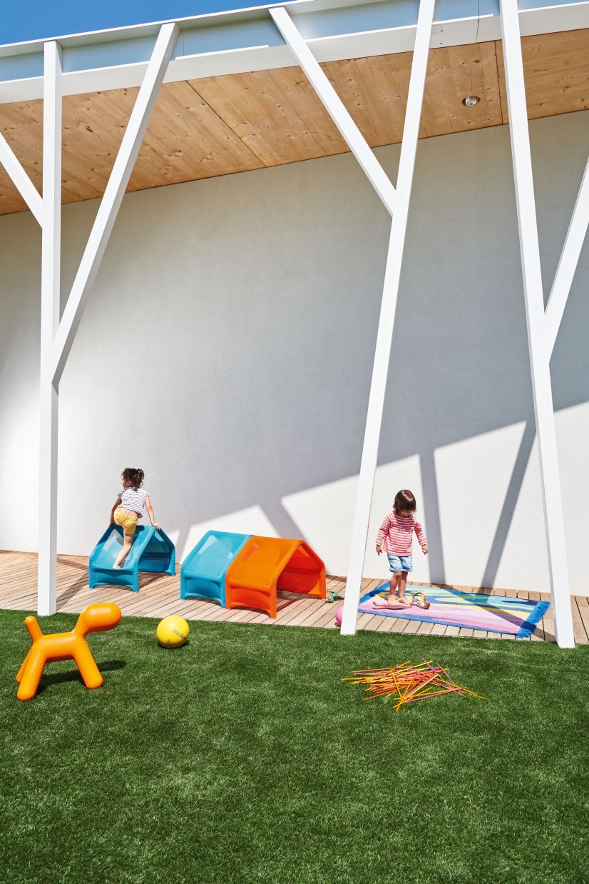 Zwei Kinder spielen im Garten mit dem Puppy Spielhund Hocker von Magis und einem Spieltunnel.