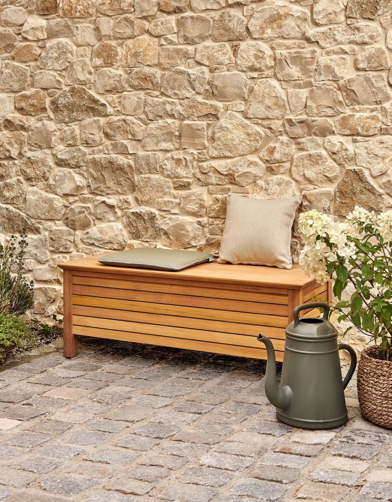 Weishäupl Deck Sitztruhe aus Holz für den Außenbereich mit Kissen und Gießkanne.