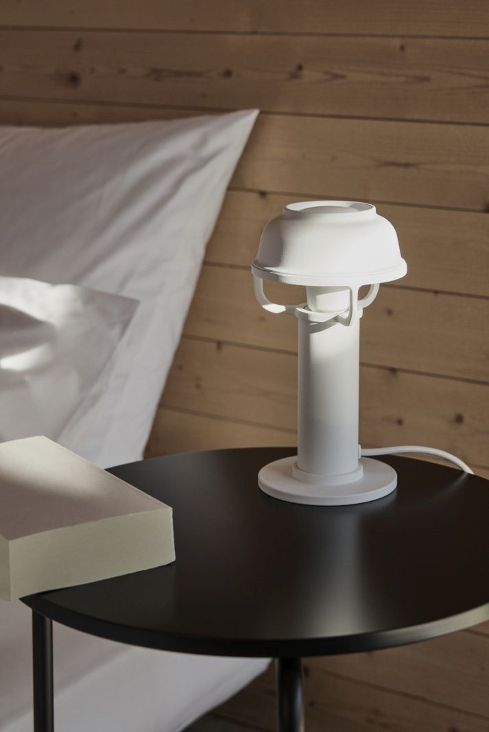 Weiße Kori Tischleuchte von Artek auf Nachttisch neben Bett und Buch.