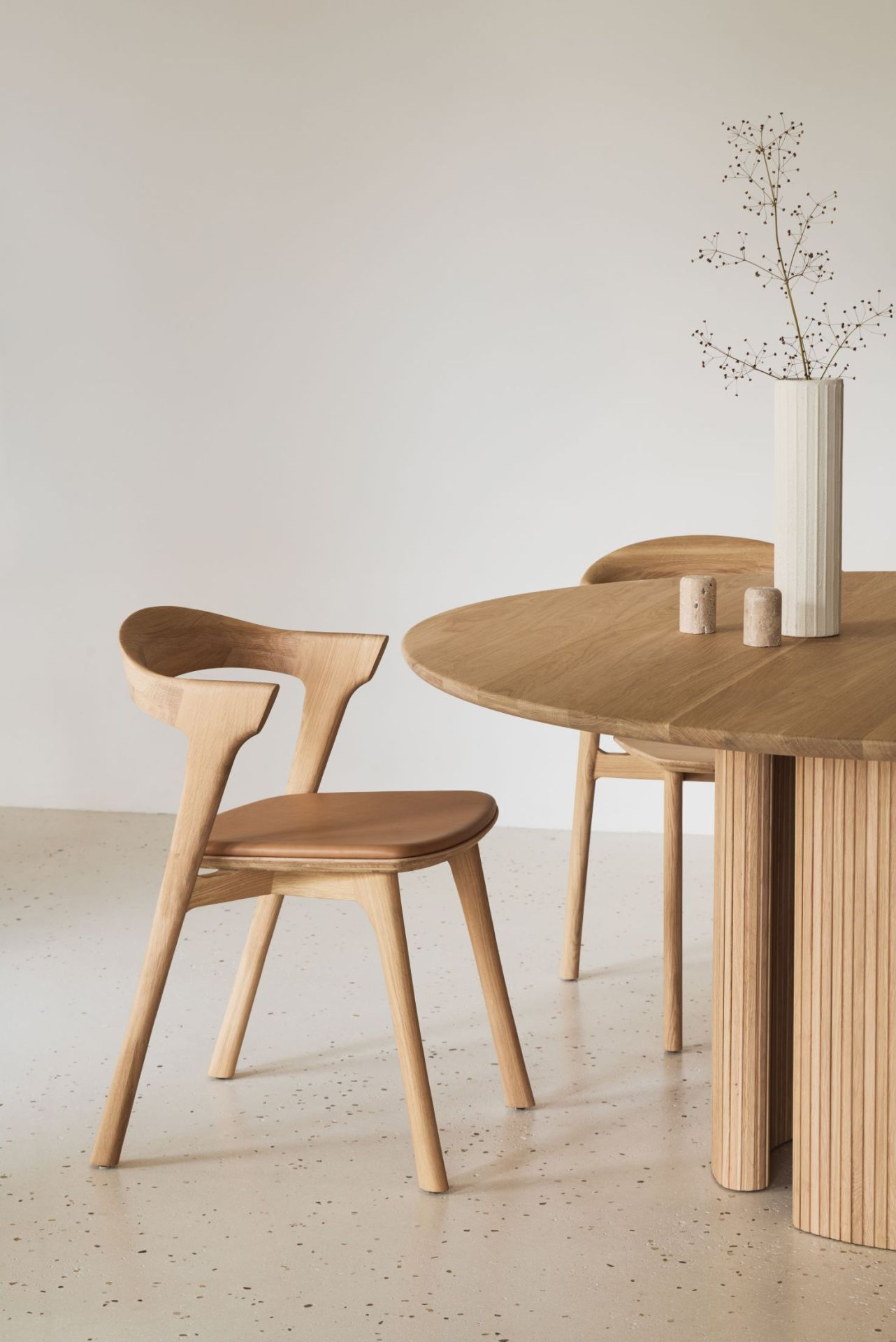 Roller Max Tisch von Ethnicraft: Runder Esstisch aus Eiche mit geriffeltem Sockel und Stühlen.