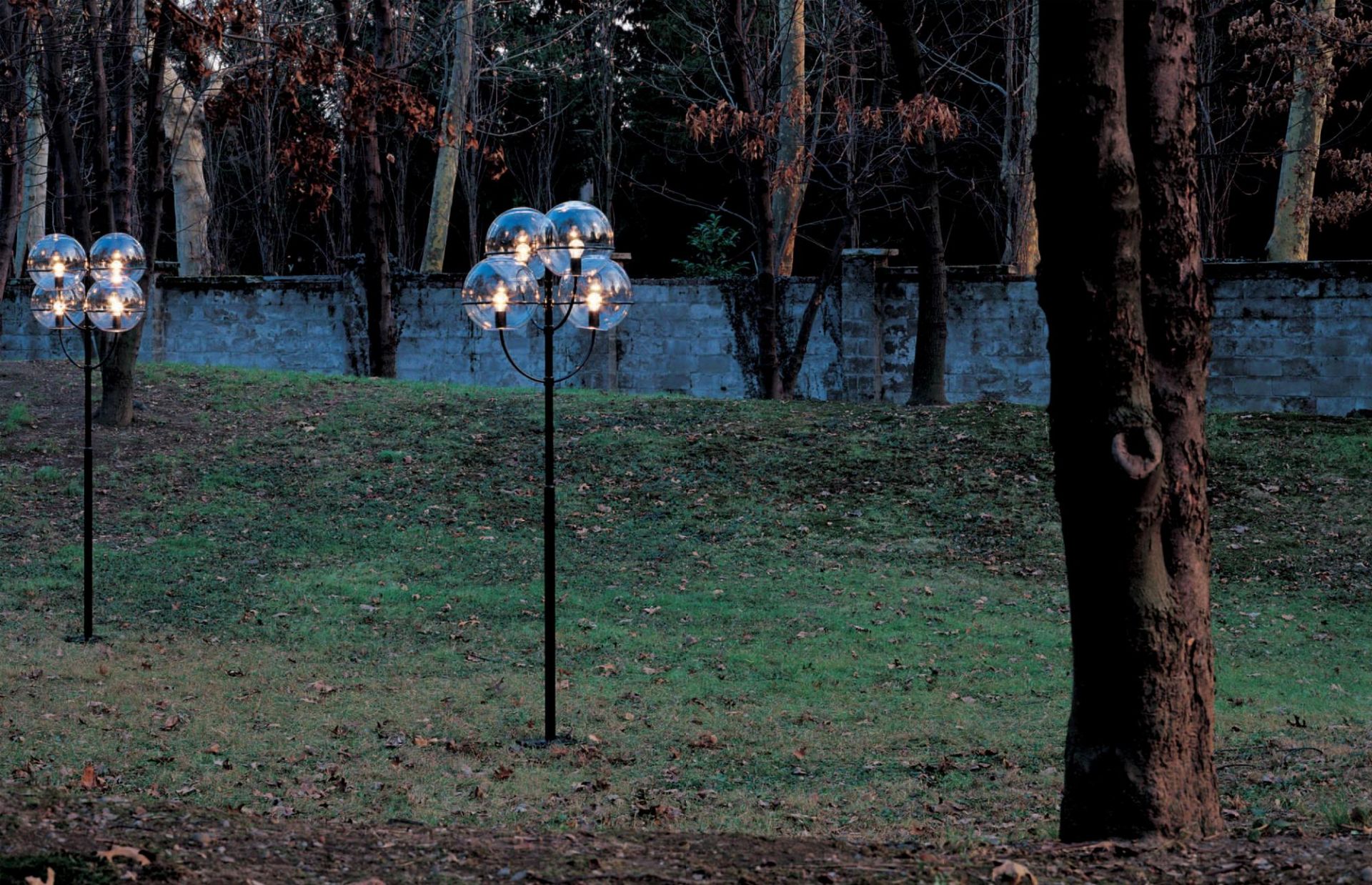 Lyndon 350 Outdoor Stehleuchte von Oluce, 200 cm, mit vier Glaskugeln im Garten.