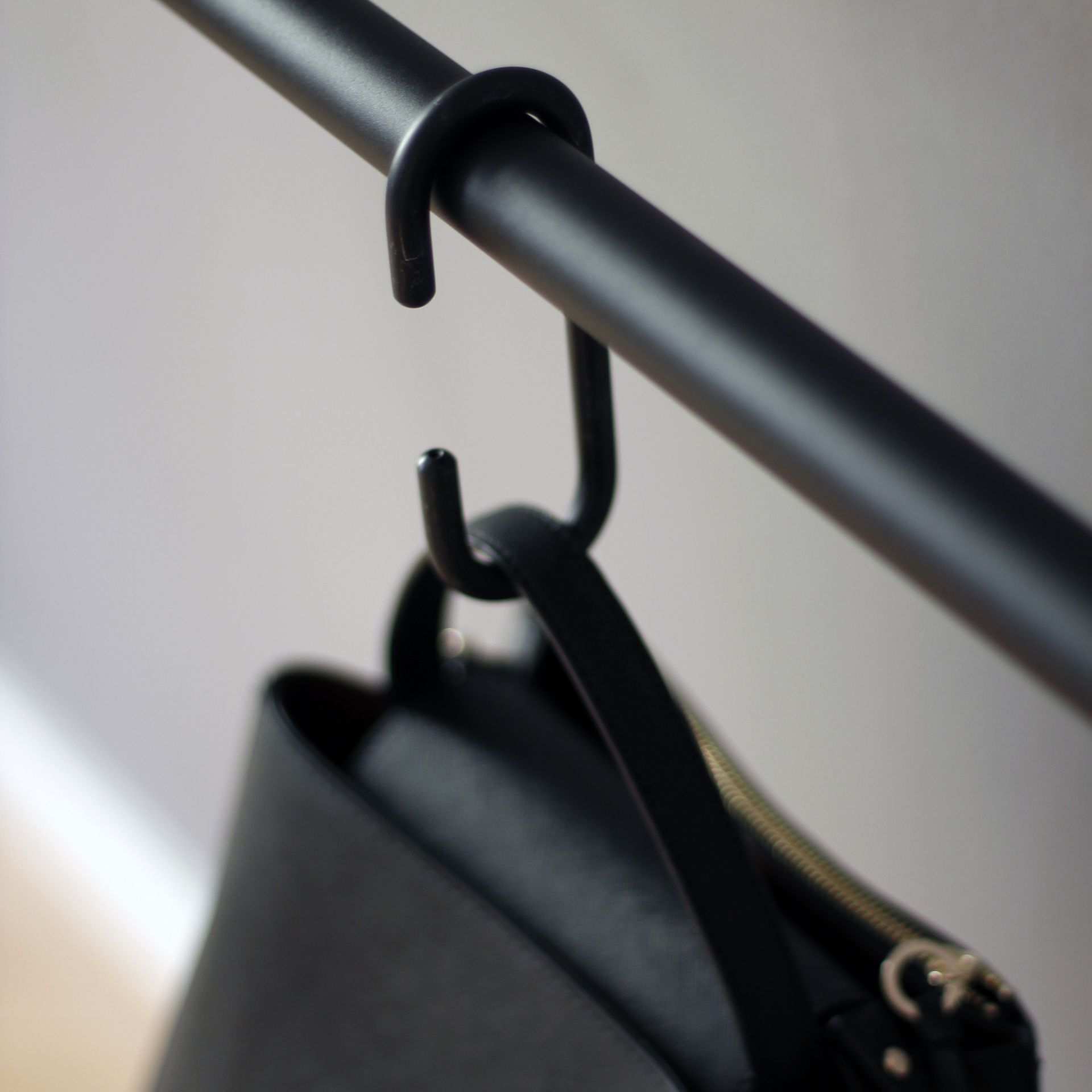 Detailaufnahme: Schwarze Leanon Anlehngarderobe mit Tasche, moderne Garderobenlösung für Flur und Büro.