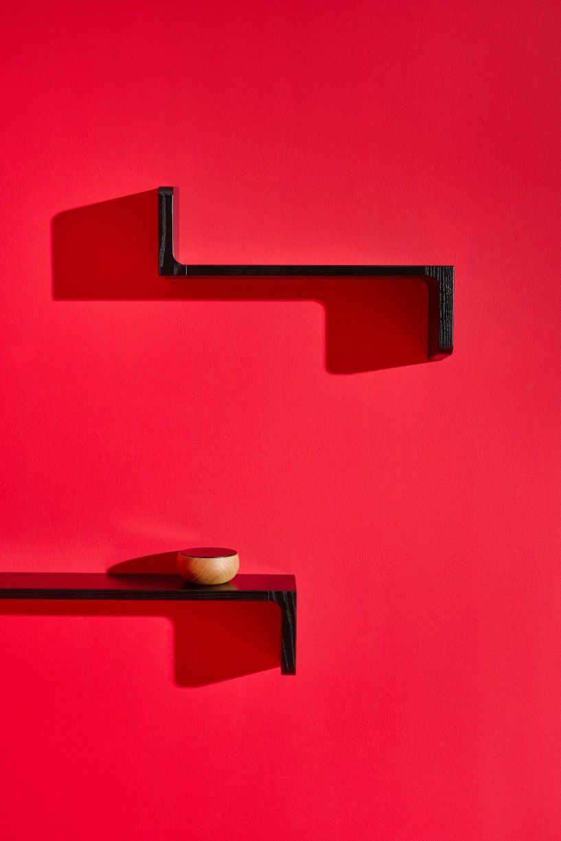 Schwarze Ulna Wandregale von Schönbuch an roter Wand, eines mit kleiner Holzschale dekoriert.