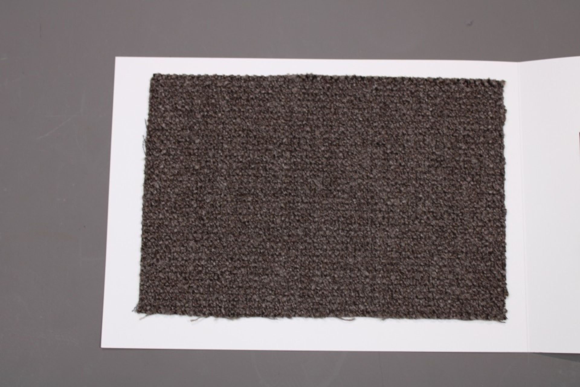 Stoffmusterkarte Gruppe 82 Cor: Nahaufnahme eines braunen, texturierten Möbelstoff-Musters auf weißem Karton.