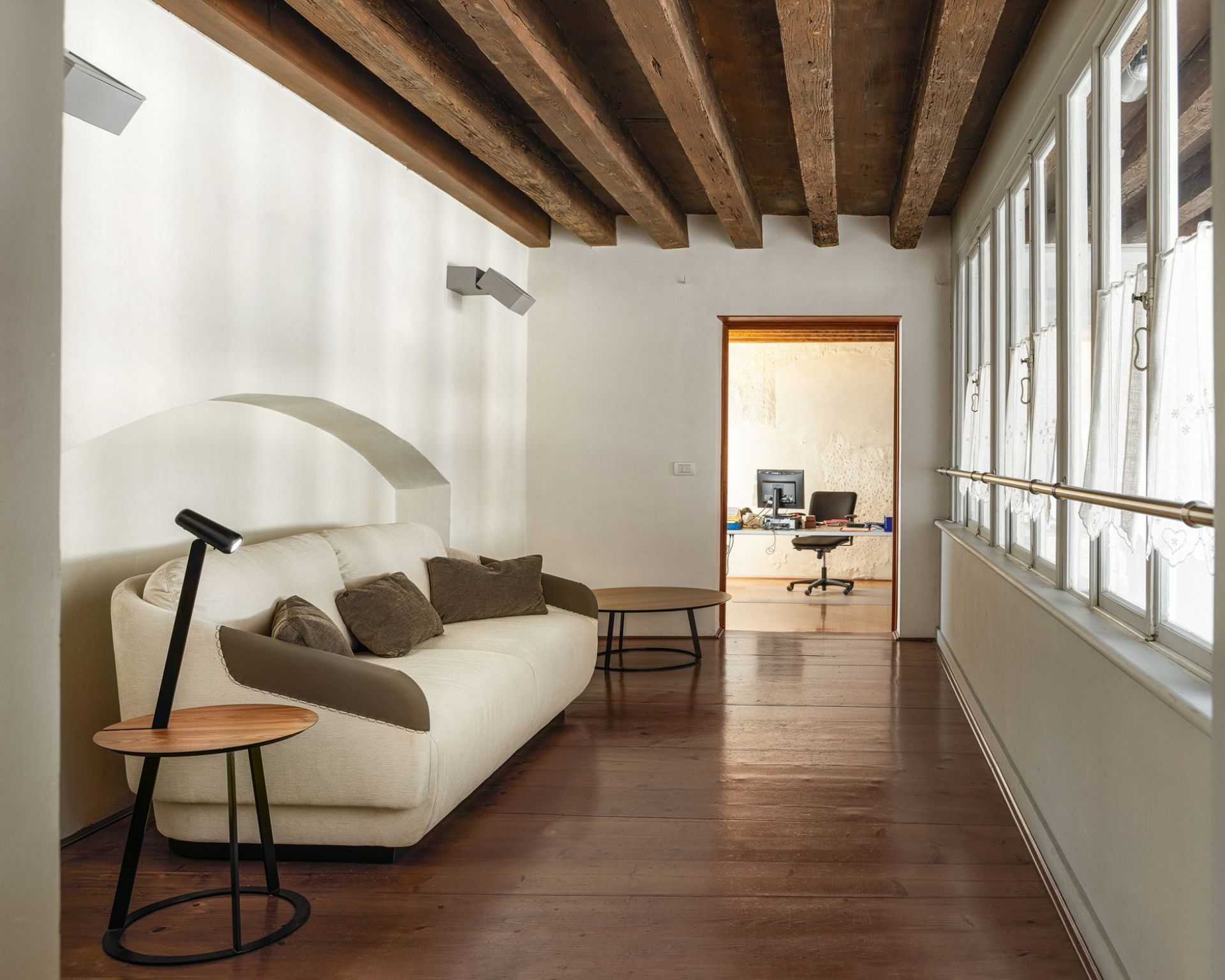 Albino Torcia Beistelltisch in Walnuss und Schwarz neben Sofa im Wohnzimmer.