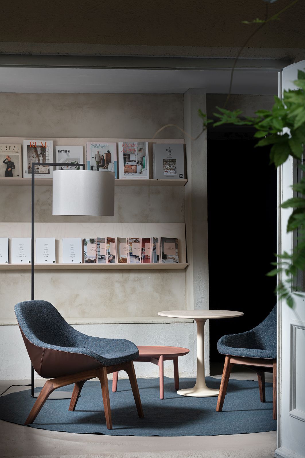 Read Noon Stehleuchte in Schwarz beleuchtet stilvolles Interieur mit Sesseln und Beistelltischen.