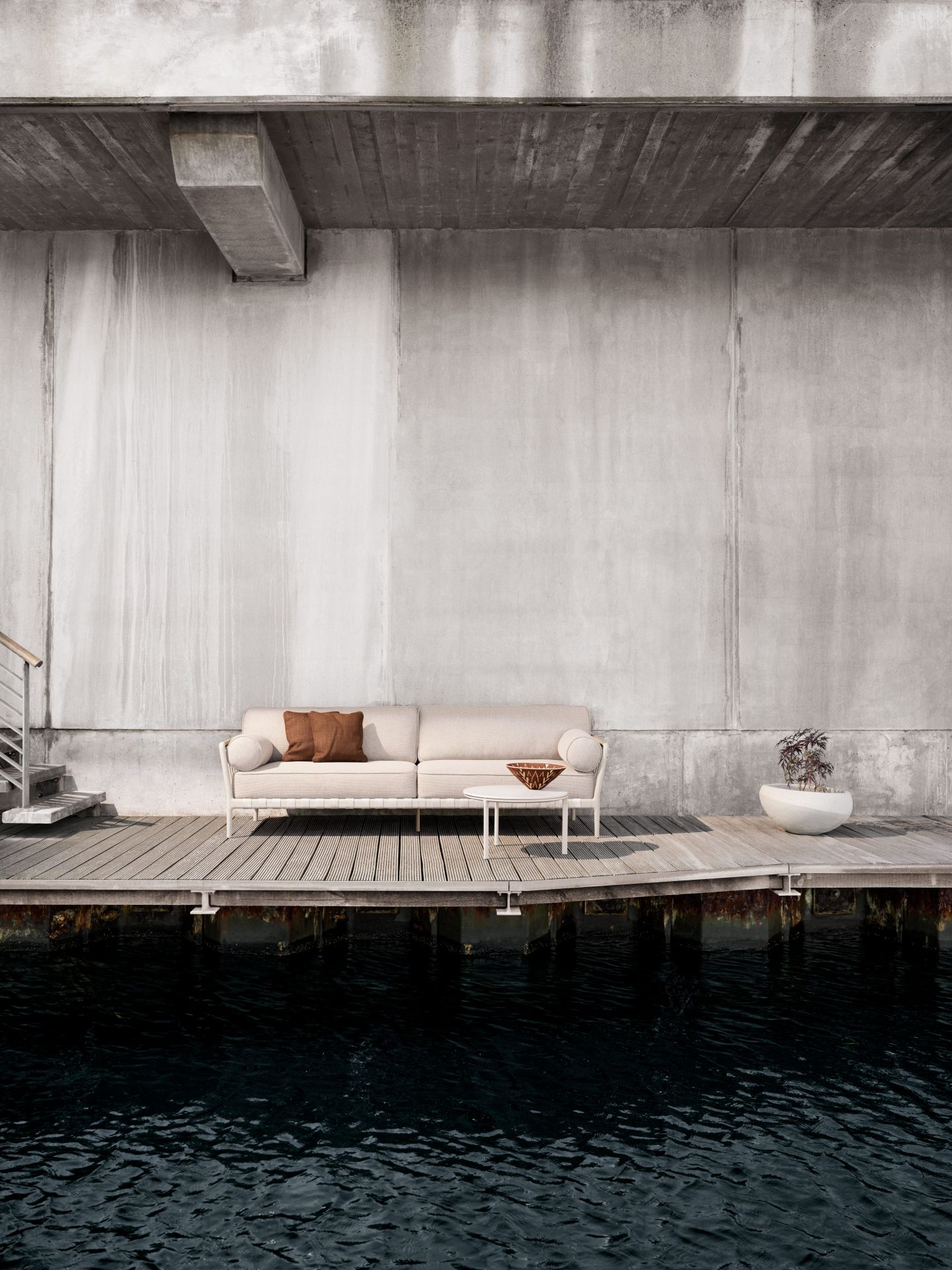 Vipp Open-Air 3-Sitzer Outdoor Sofa auf Holzterrasse am Wasser, minimalistisches Design.