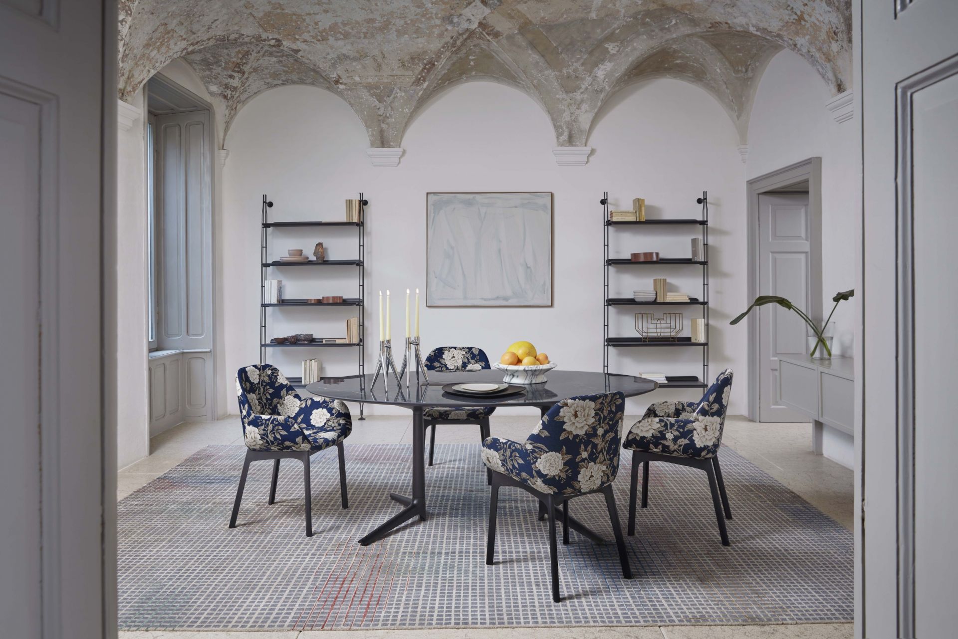 Esszimmer mit Adam Wood Regal in Schwarz, Esstisch und floralen Stühlen.