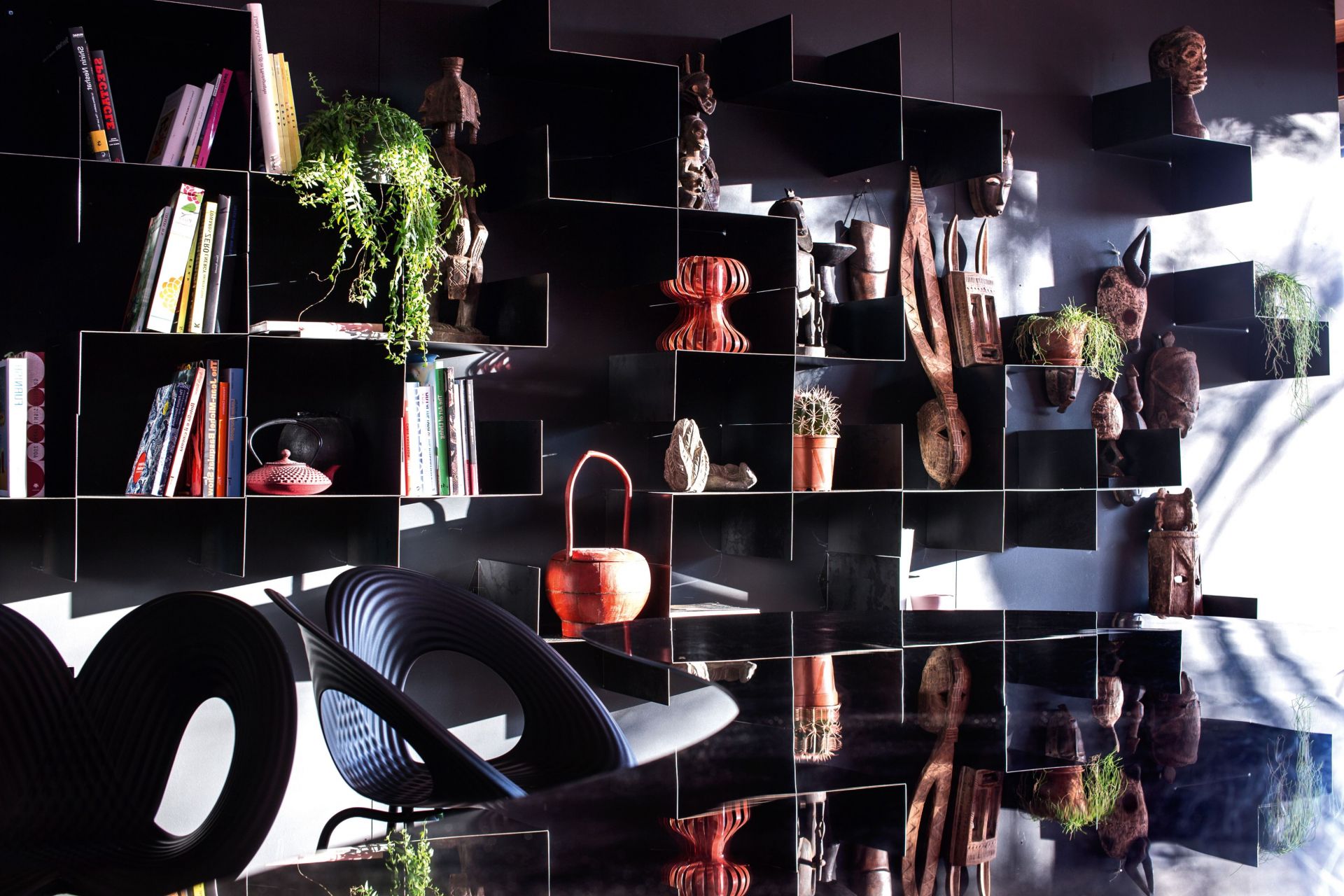 Moroso Z-Shelf 4er Set links, schwarzes modulares Wandregal mit Deko-Objekten und Design-Stühlen im Wohnzimmer.