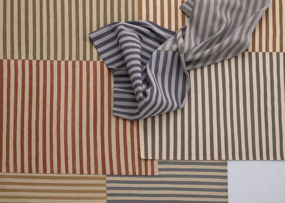 Detailaufnahme des Nanimarquina Ceras Teppichs mit bunten Streifen und einem gestreiften Tuch.