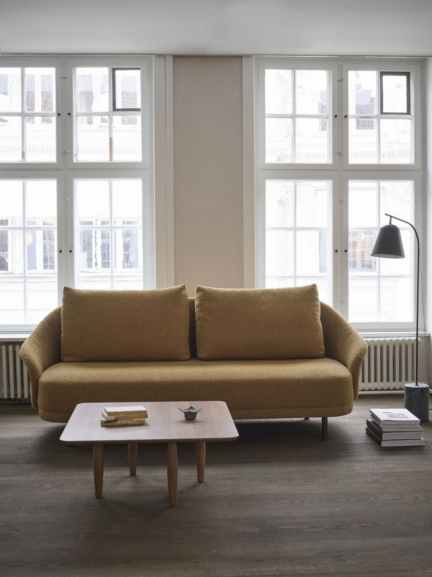 Oku Couchtisch aus Eiche dunkel geräuchert von Norr11 vor Sofa und Fenstern.