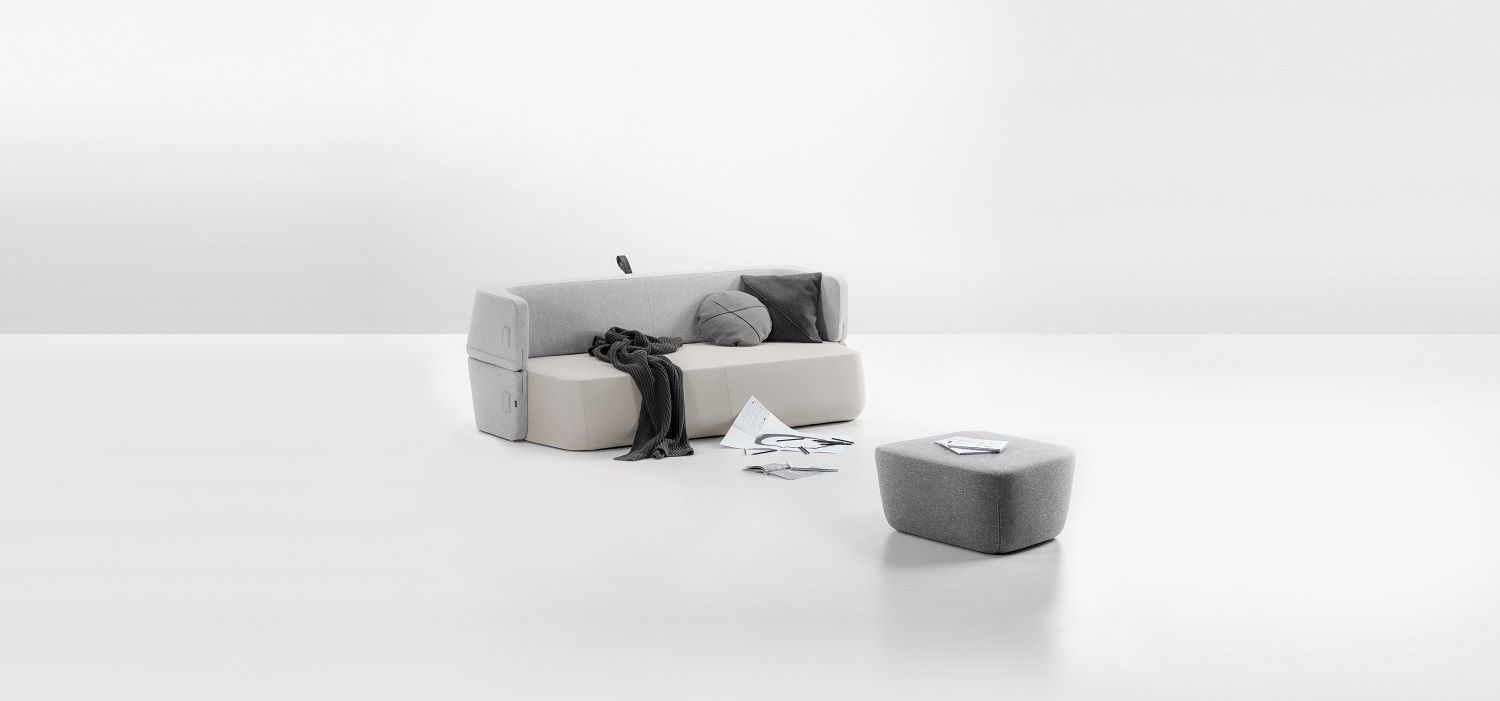 Helles Studiofoto des Revolve Schlafsofas von Prostoria mit Hocker und Kissen.