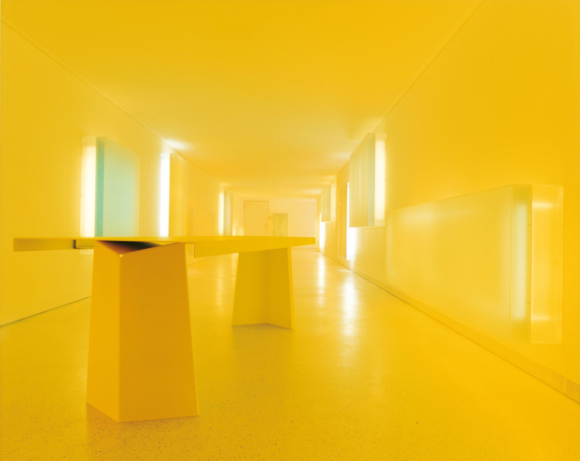 Gelber Pallas Tisch von ClassiCon in einem Flur mit gelbem Boden und Wänden.