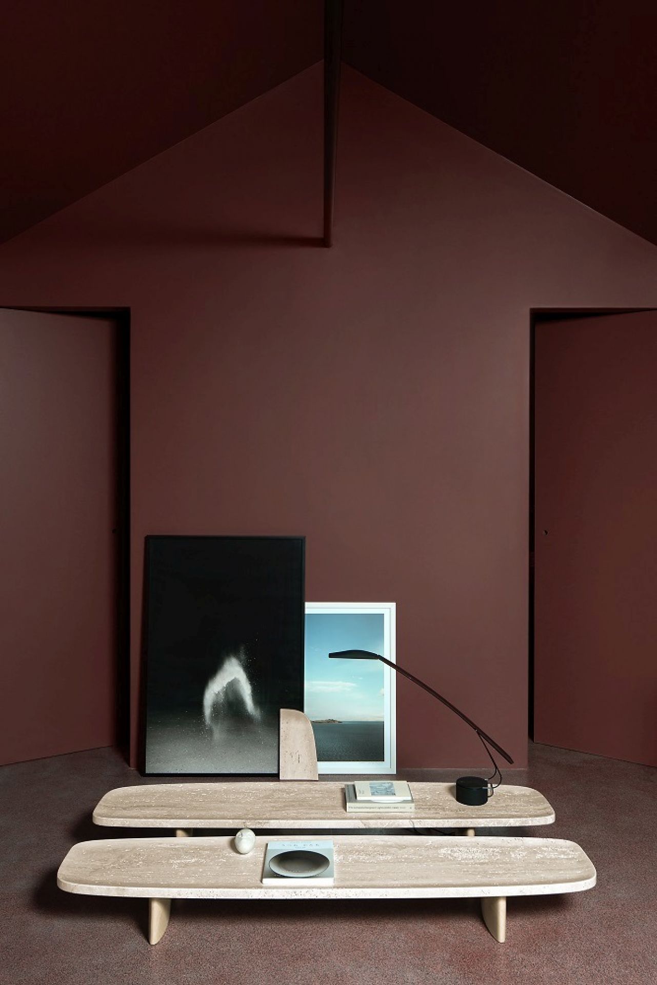 Classicon Matéria Long Table Beistelltisch aus Travertin, mit Deko-Objekten und Lampe, vor braunem Hintergrund.