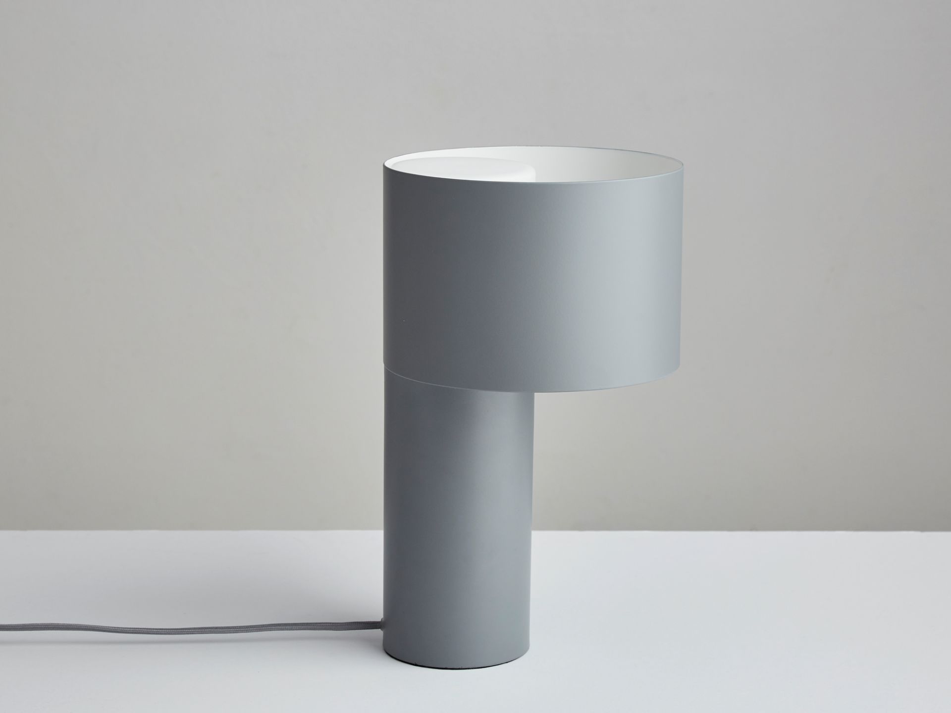 Nahaufnahme der grauen Tangent Table Lamp Tischleuchte von Woud mit zylindrischem Lampenschirm.