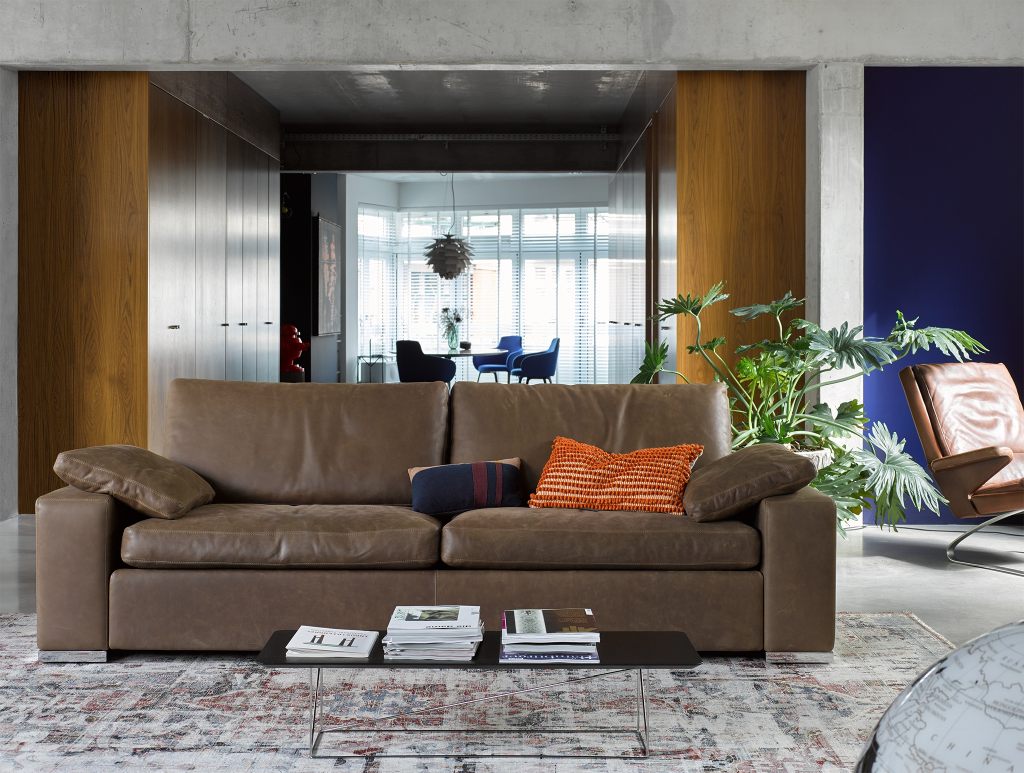 Braunes Conseta Sofa von Cor im modernen Wohnzimmer mit Kissen und Teppich. Ledersofa für stilvolles Wohnen.