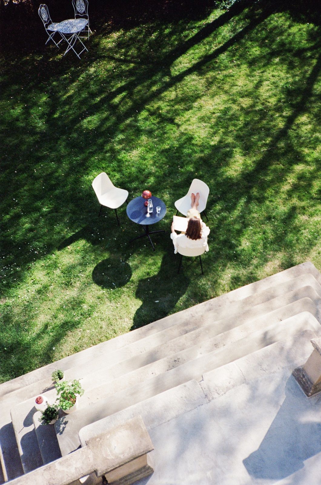 Draufsicht: Frau liest im Garten auf einem weißen AndTradition Rely HW70 Stuhl.