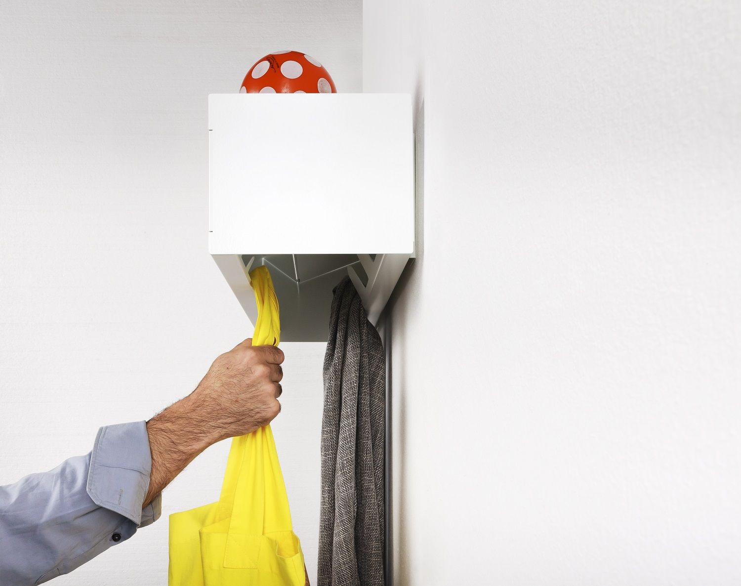Weiße Wandgarderobe CR Linea von Müller Möbelwerkstätten mit gelber Tasche und Jacke, minimalistisches Design.