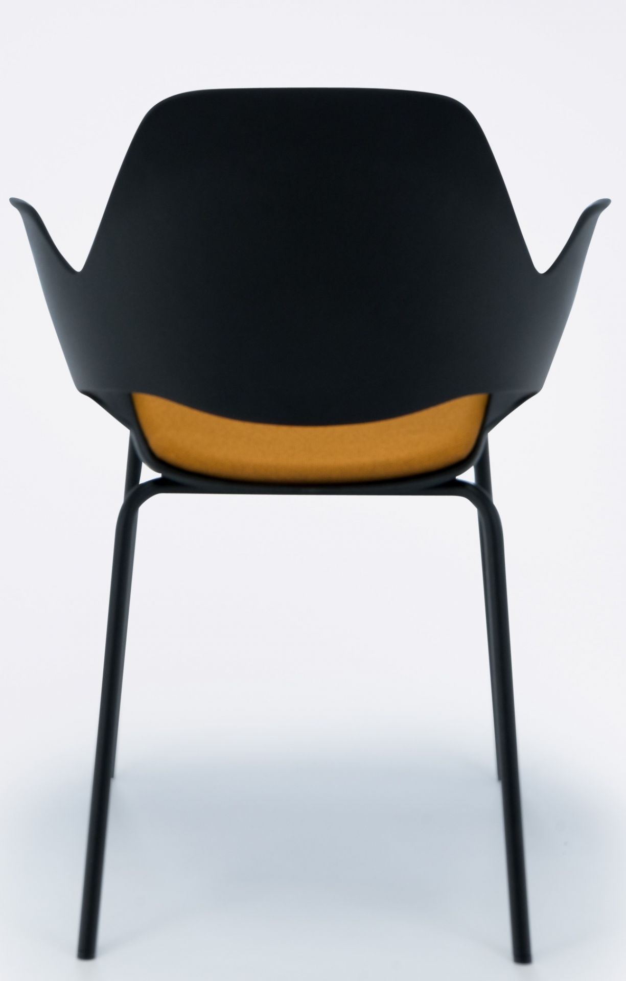 Falk Stuhl von Houe, Ansicht von hinten, schwarze Sitzschale, gelbes Kissen, Metallbeine.