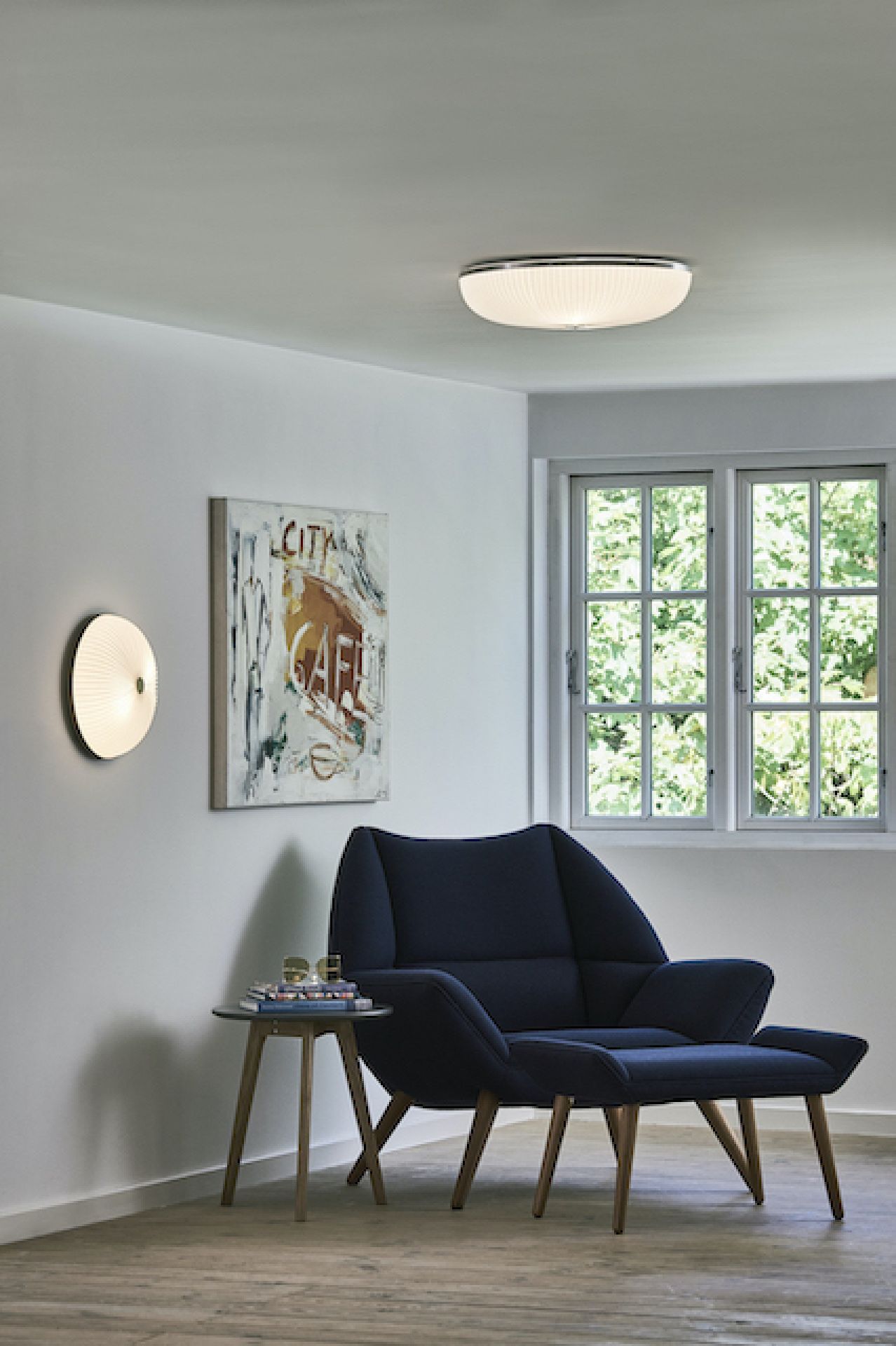 Lamella Deckenleuchte von Le Klint, goldene Wandleuchte im modernen Wohnzimmer mit Sessel.