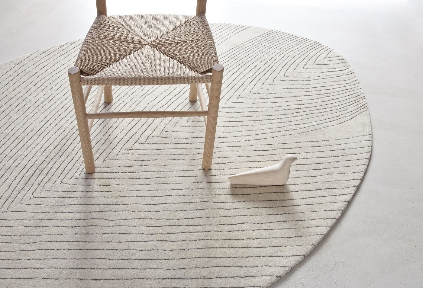 Nanimarquina Quill Teppich 150x260 cm mit Stuhl und Deko-Vogel. Moderner Teppich mit Streifenmuster.