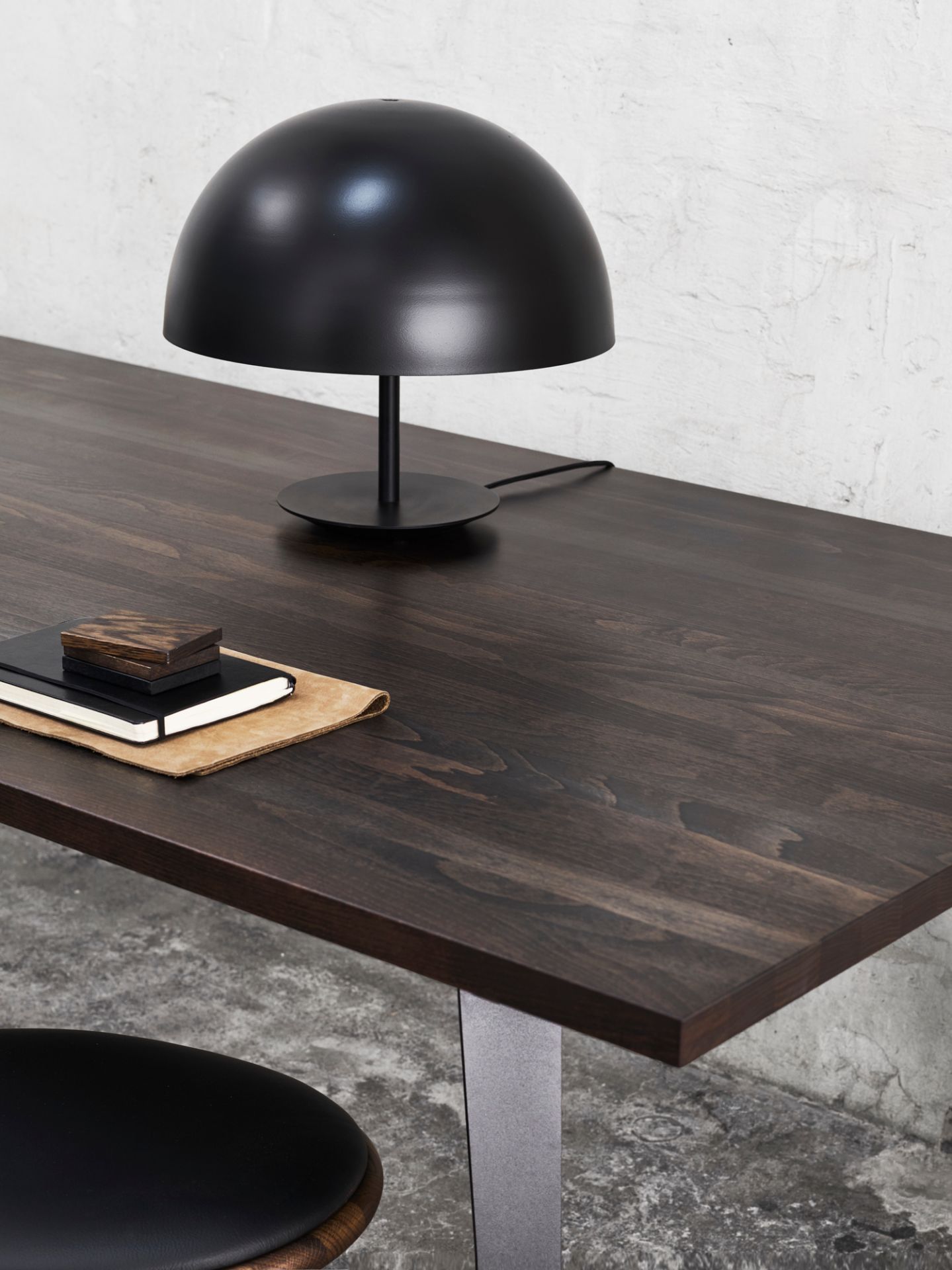 Schwarze Baby Dome Lampe von Mater auf dunklem Holztisch mit Notizbüchern.