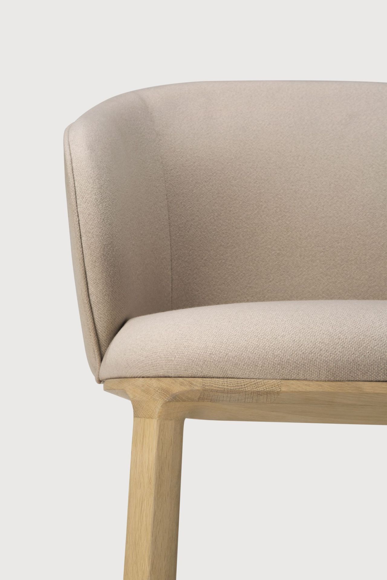Detailaufnahme vom Unda Stuhl mit Eichenholzrahmen und beigem Stoffbezug, modernes Stuhldesign für Esszimmer.