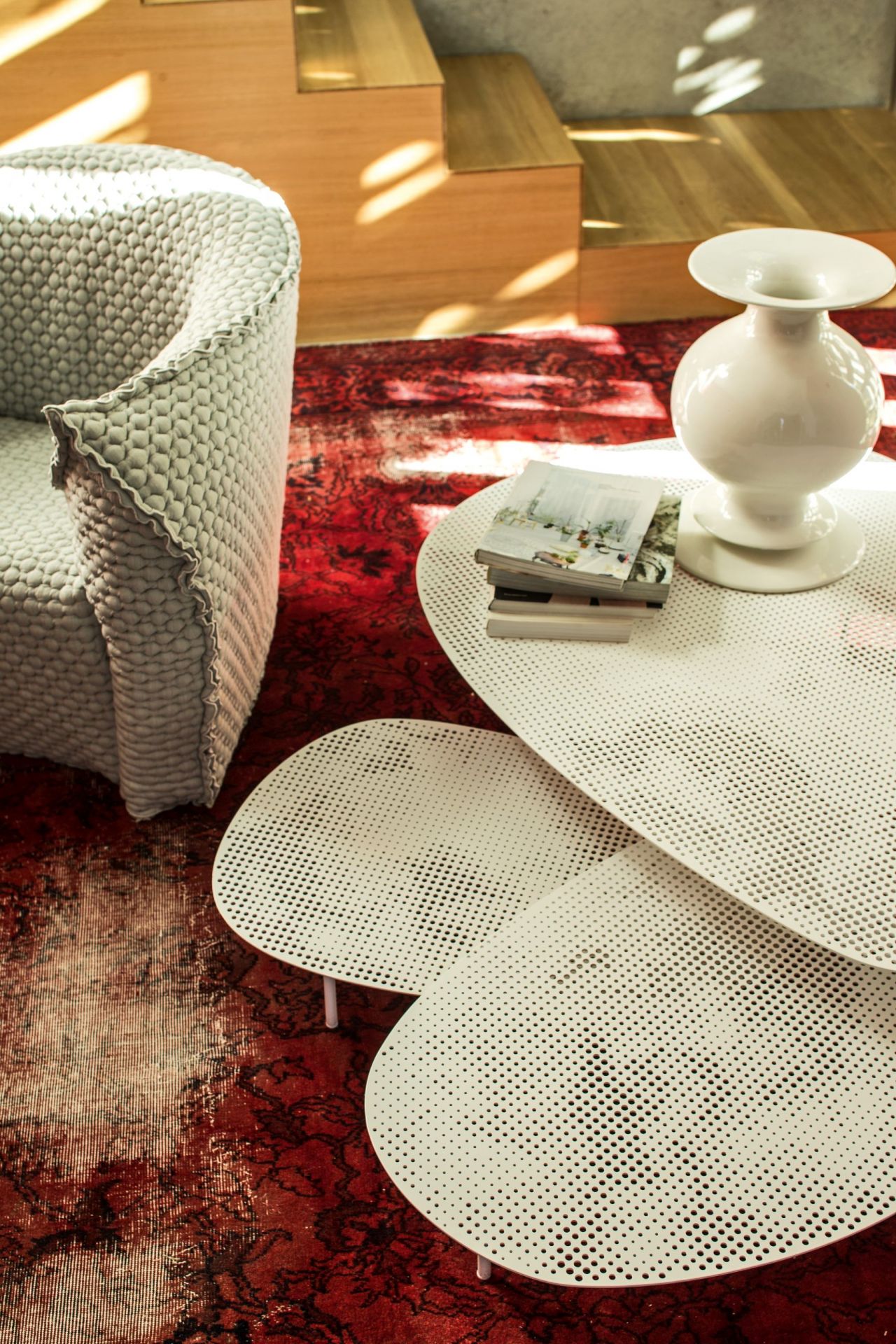 Cloud Tisch von Moroso, ein moderner, weißer Couchtisch mit durchbrochenem Design auf einem roten Teppich.