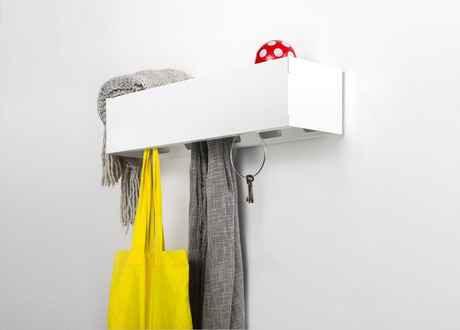 Weiße CR Linea1 Wandgarderobe von Müller Möbelwerkstätten mit Schal, Tasche und Schlüssel an der Wand.