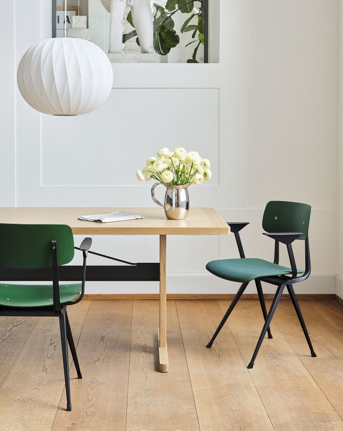 Grüne Result Armchair Armlehnenstühle von Hay an einem Holztisch mit Blumen und Lampe.