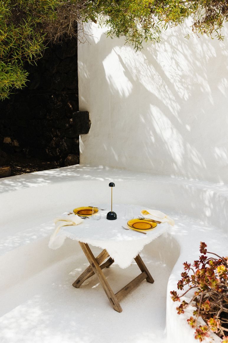 Sips Akkuleuchte in Grün/Gold auf gedecktem Tisch im Freien. Marset Tischleuchte für stimmungsvolle Beleuchtung.