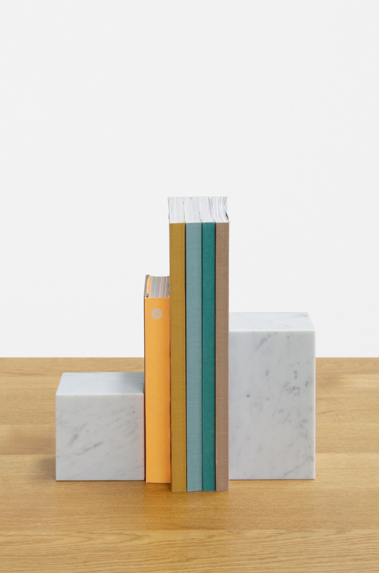 Weiße AC11 Stop Buchstütze von e15 aus Marmor hält farbige Bücher auf einem Holztisch.