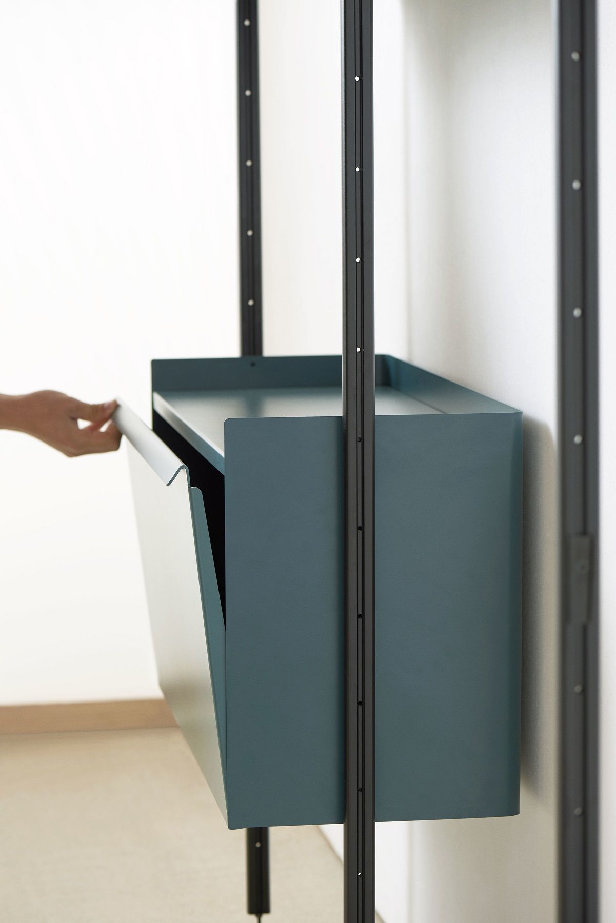 Detailaufnahme des Pier System Regals in Stahlblau mit Aluminiumrahmen, Schublade wird geöffnet.