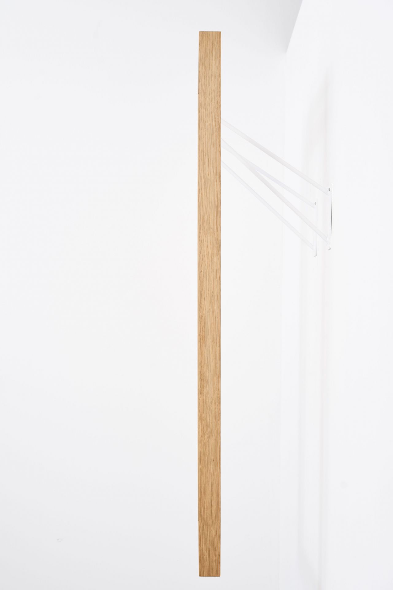 gardero-b Wandgarderobe: Minimalistische Garderobe aus Holz mit weißen, filigranen Aufhängungen an einer weißen Wand.