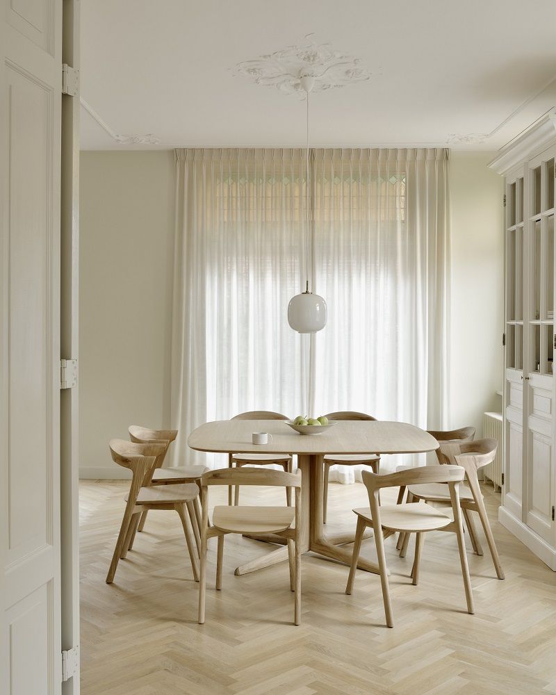 Quadratischer Esstisch von Ethnicraft aus hellem Holz mit passenden Stühlen in einem hellen Esszimmer.