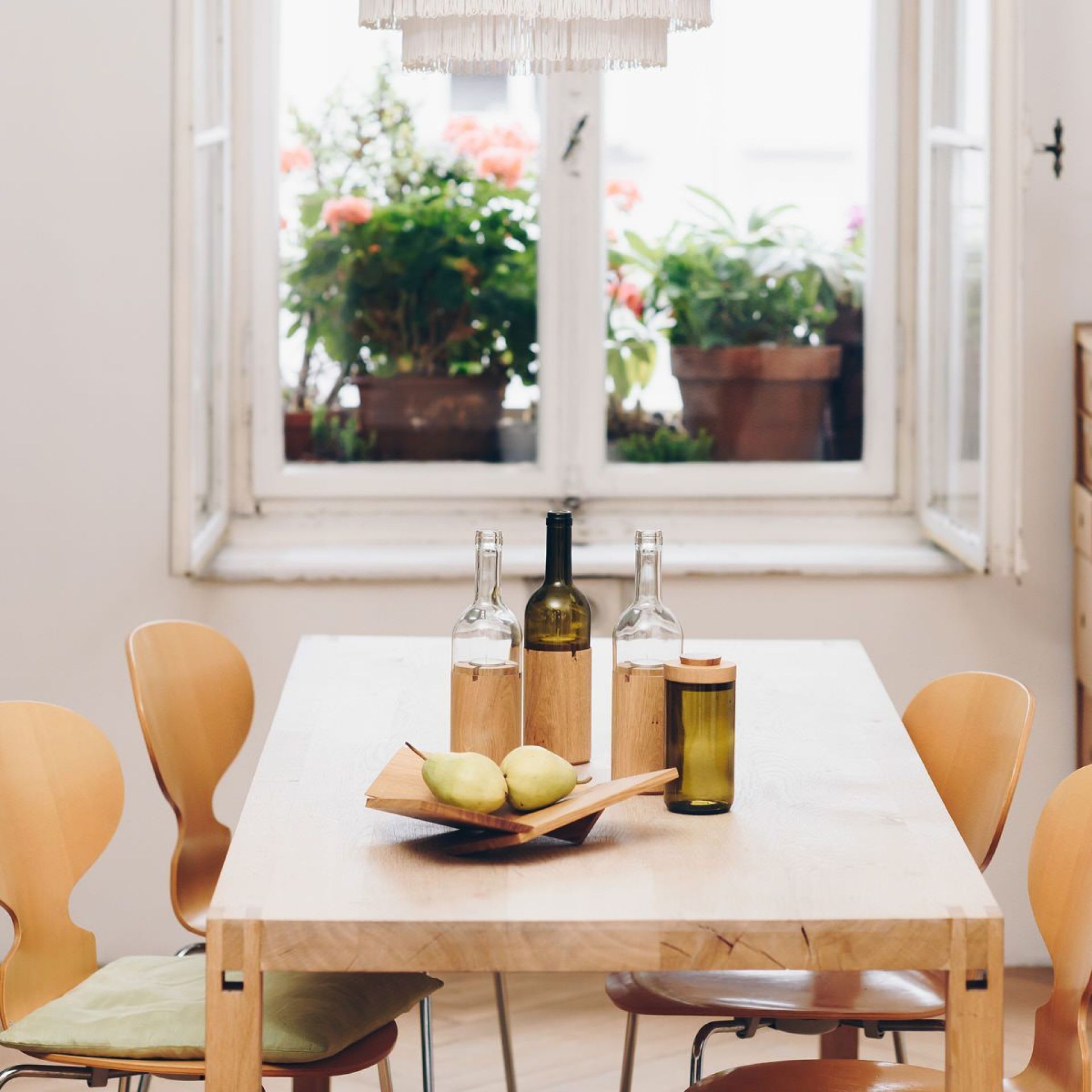 Grüne Side by Side Dose und Vasen als Deko auf Esstisch mit Holzschale und Birnen.