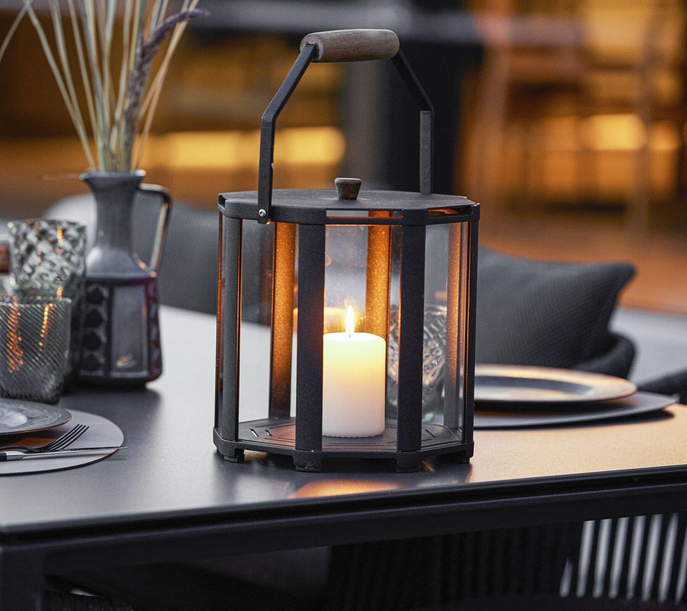 Lightlux Laterne Mini: Schwarze Outdoor Laterne mit Teakholzgriff und brennender Kerze.