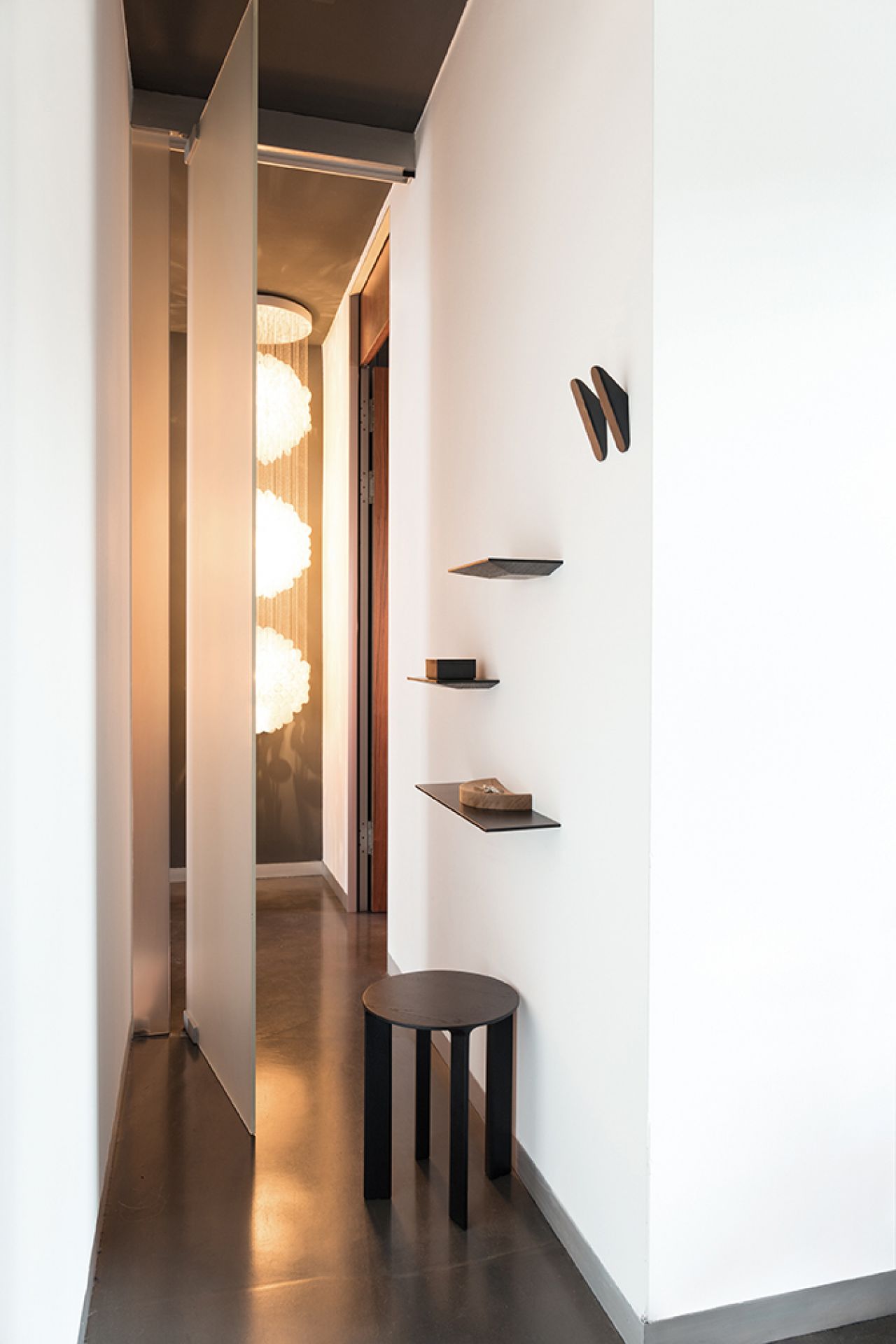 Schönbuch Cut Wandablage aus Eiche natur geölt an weißer Wand mit Deko und Hocker.