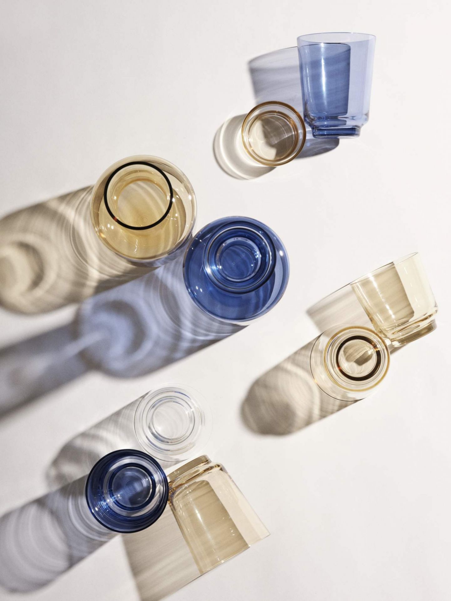 Ansicht von oben: Muuto Raise Karaffe und Gläser in Blau, Gelb und Klar.