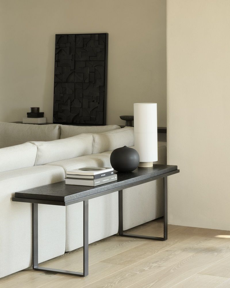 Ethnisch anmutende "Stability" Konsole von Ethnicraft in Minerals Umber mit Deko-Elementen neben einem Sofa.