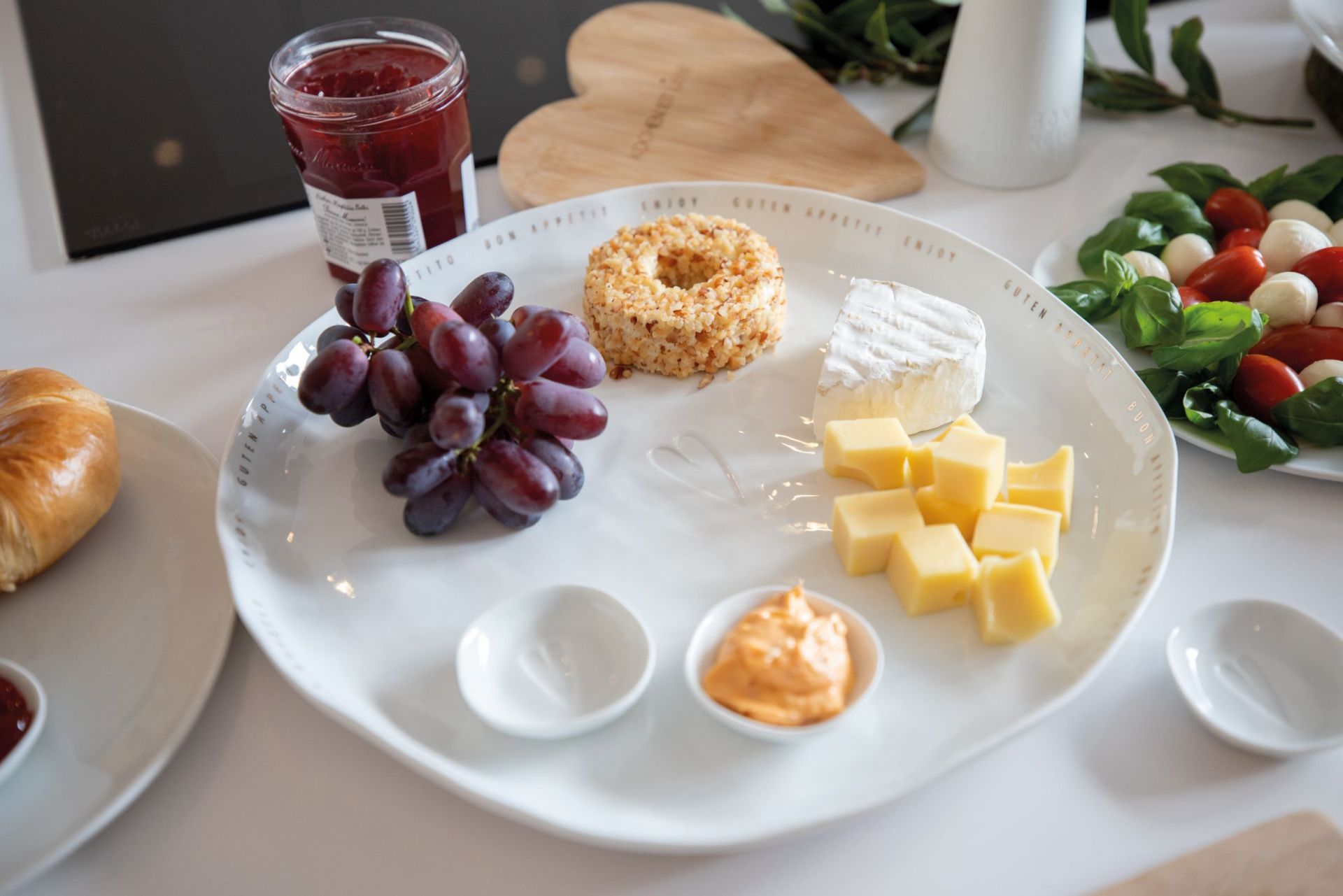 Guten Appetit Platte Räder: Servierplatte mit Käsewürfeln, Camembert, Trauben und Dips für Feinschmecker.