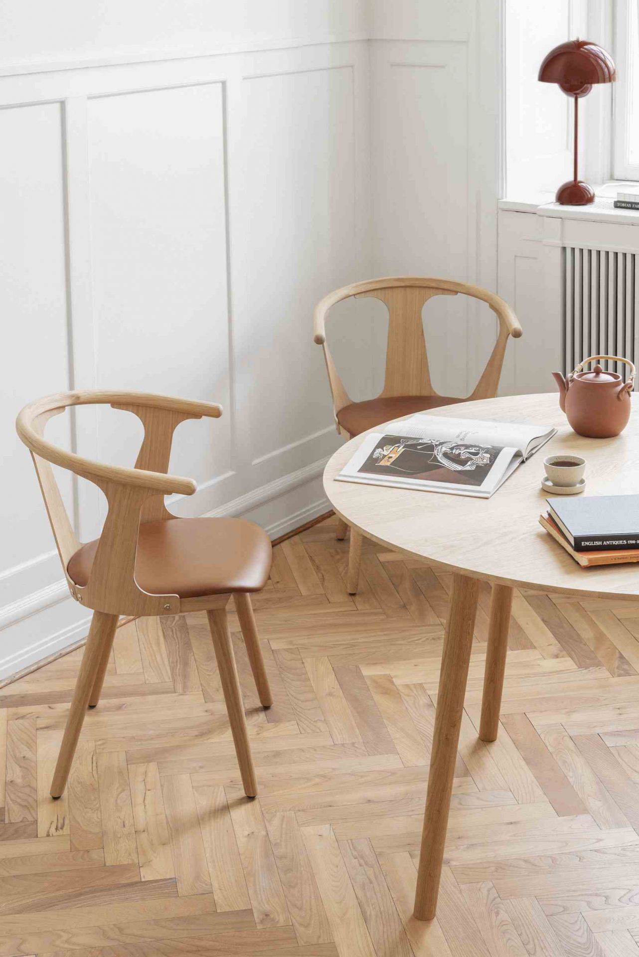 AndTradition In Between Table SK3 mit Stühlen in hellem Holz und Leder auf Parkettboden.