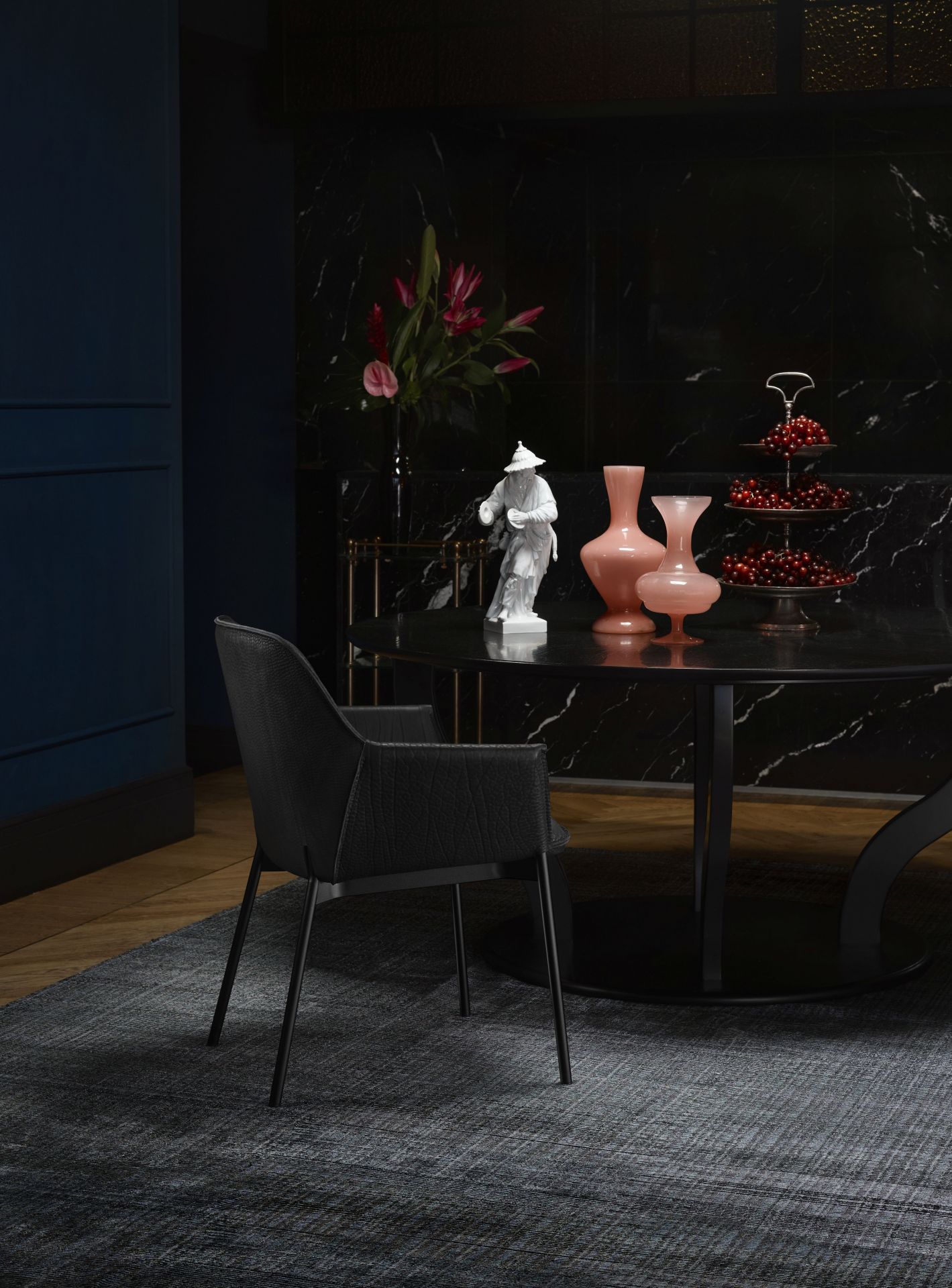 Schwarzer Marla Armlehnstuhl von Freifrau Manufaktur mit hohen Armlehnen vor dunklem Hintergrund. Design Stuhl für Esszimmer.