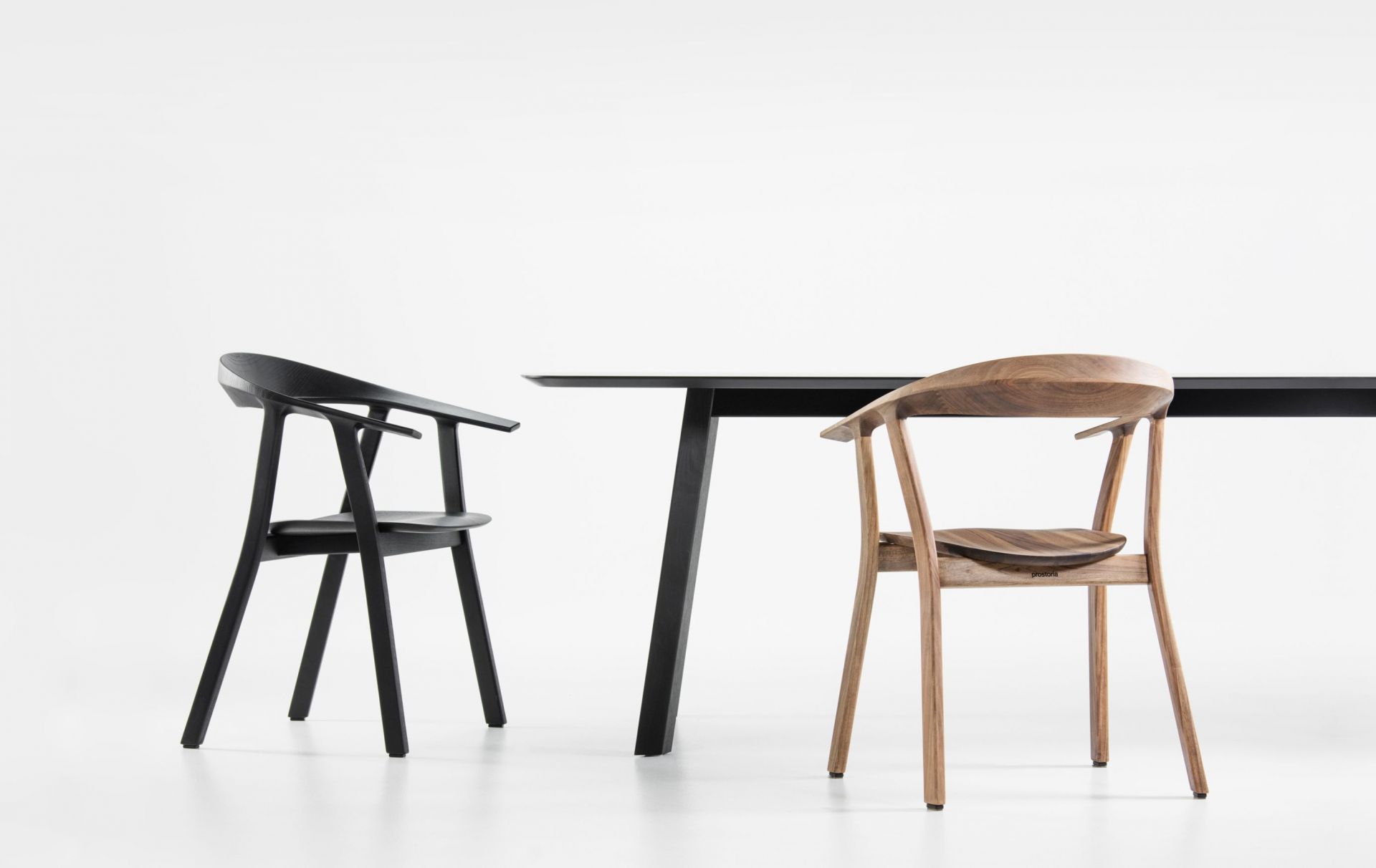 Rhomb Tisch von Prostoria mit zwei Stühlen in Schwarz und Naturholz vor weißem Hintergrund.