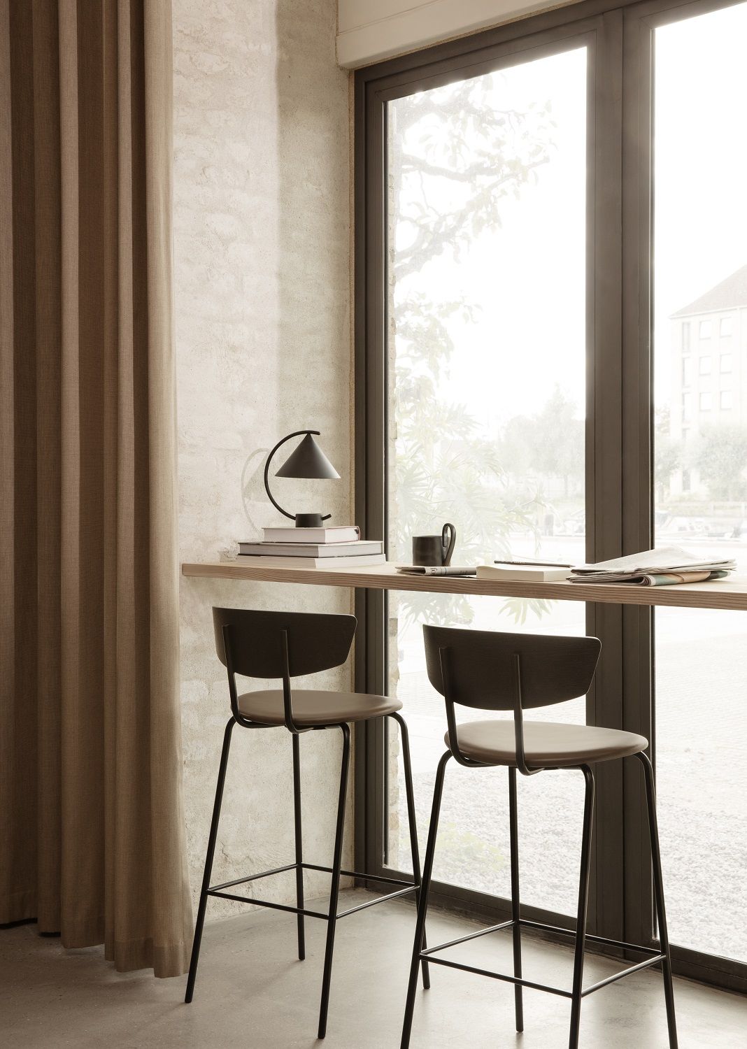 Meridian Lampe von Ferm Living als Akkuleuchte auf Tisch mit Stühlen am Fenster.