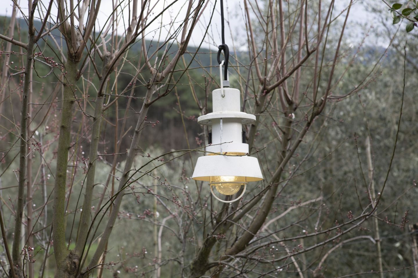 Martinelli Luce Polo Outdoor Pendelleuchte, weiße Hängelampe im Garten zwischen Ästen.
