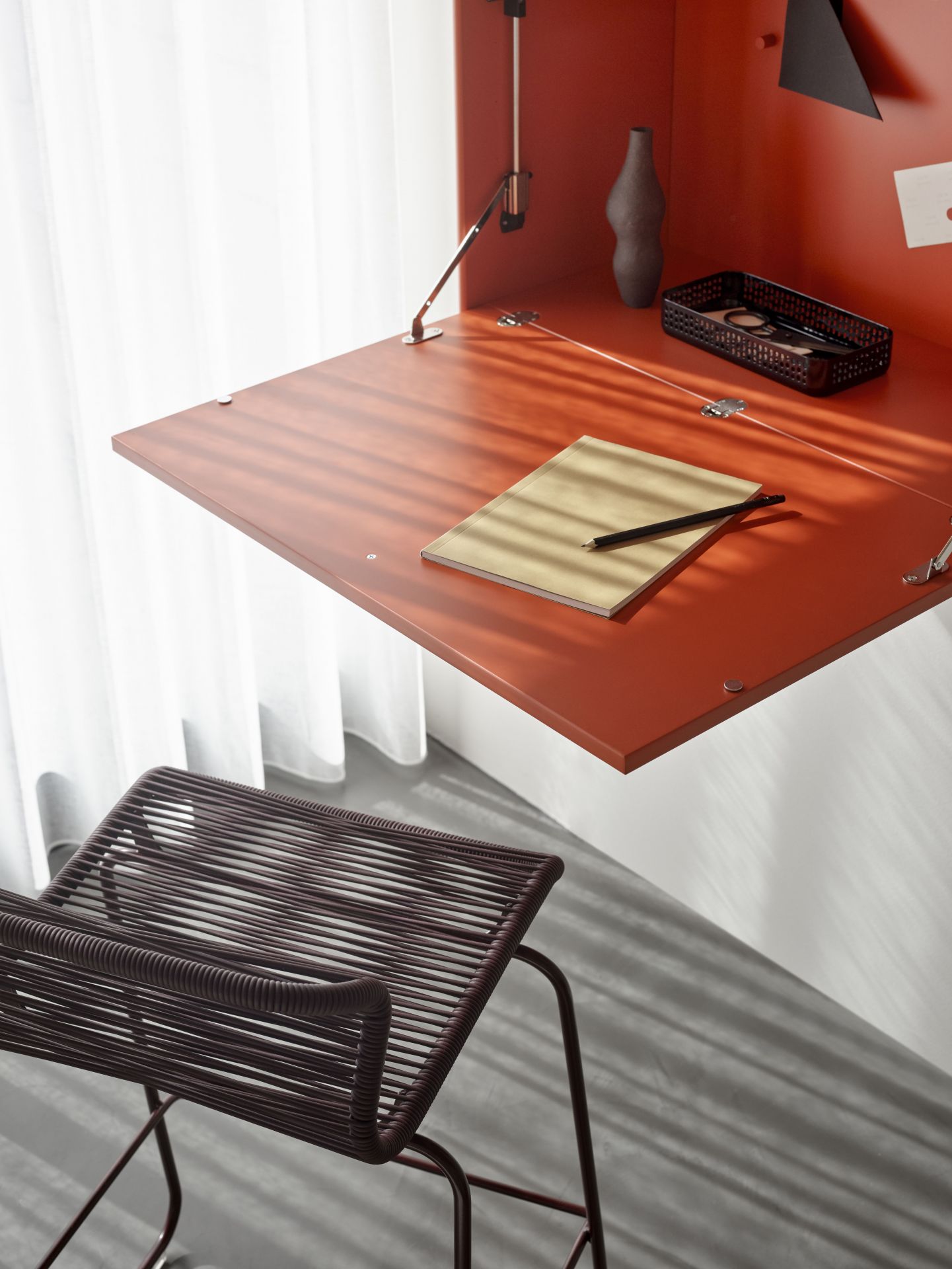 Nahaufnahme des STUDIO Sekretärs Montana in Rot mit Stuhl, Notizblock und Stift.