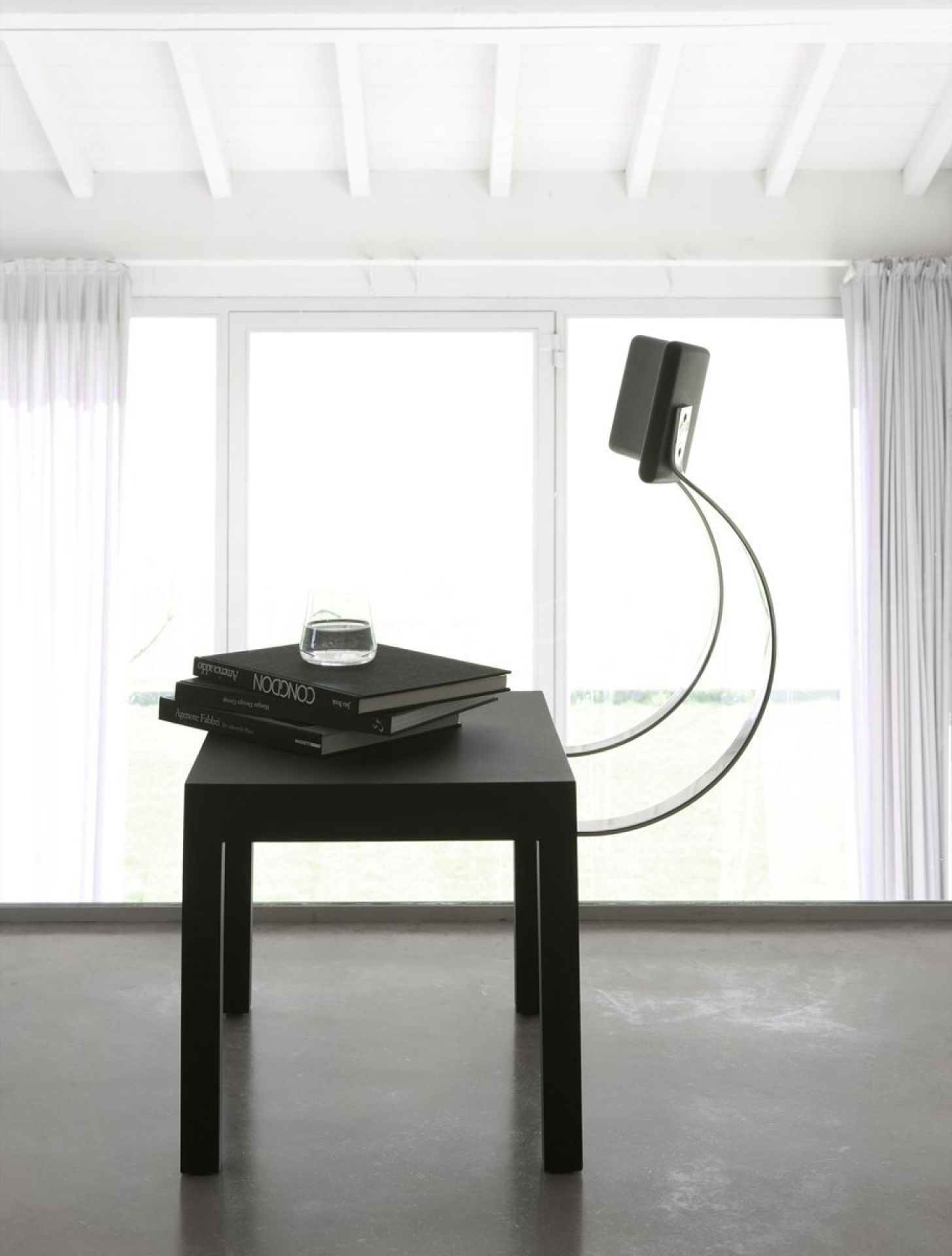 Schwarzer Follia Stuhl von Zanotta, minimalistisches Design, neben einem schwarzen Tisch mit Büchern und Wasserglas.