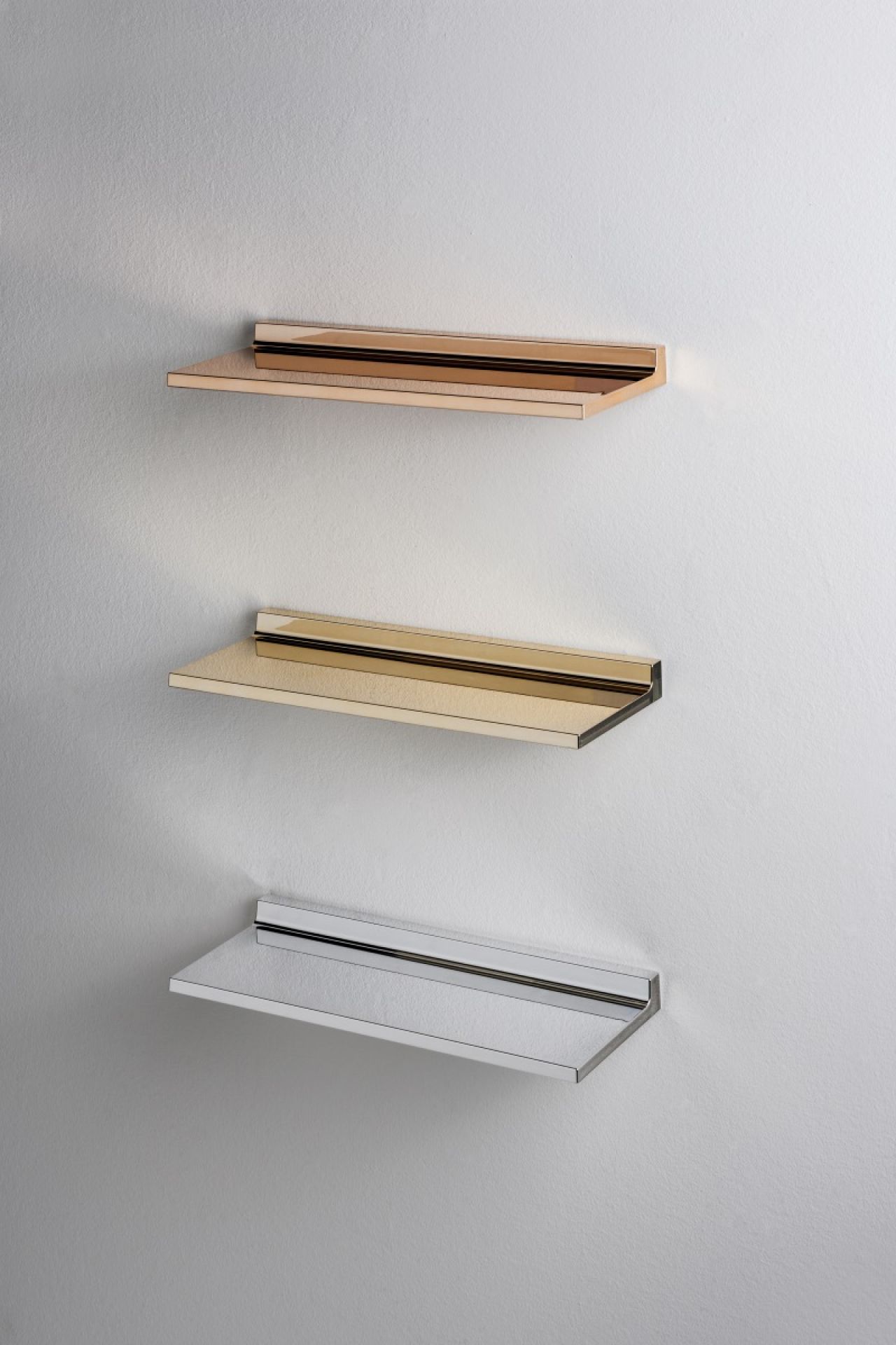 Drei Shelfish Regale von Kartell in Kupfer, Gold und Silber an einer weißen Wand.