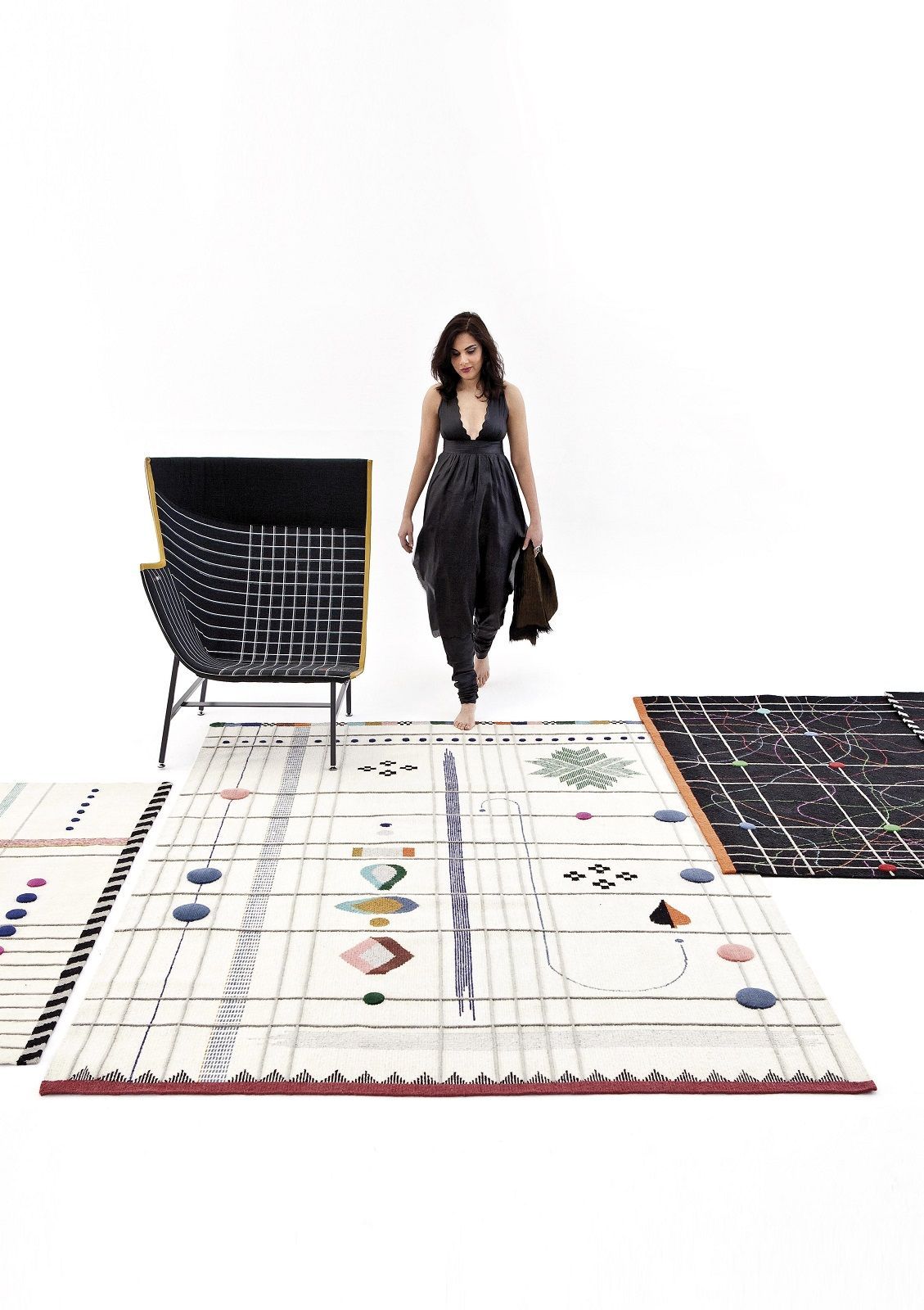 Frau barfuß auf dem Nanimarquina Rabari Teppich mit geometrischen Mustern und passendem Sessel.